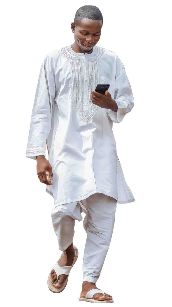 Young african man in white traditional attire walking while texting on his smartphone
